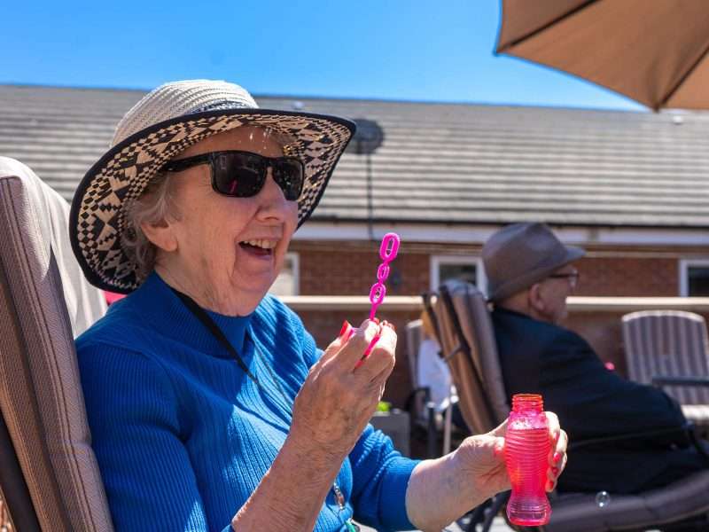 Senior woman enjoying bubbles outdoors.