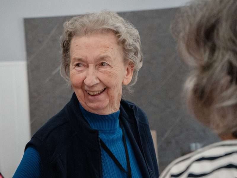 Smiling elderly woman interacting in a common area.