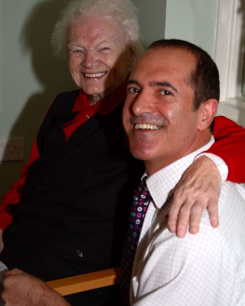 Smiling elderly resident and staff member indoors