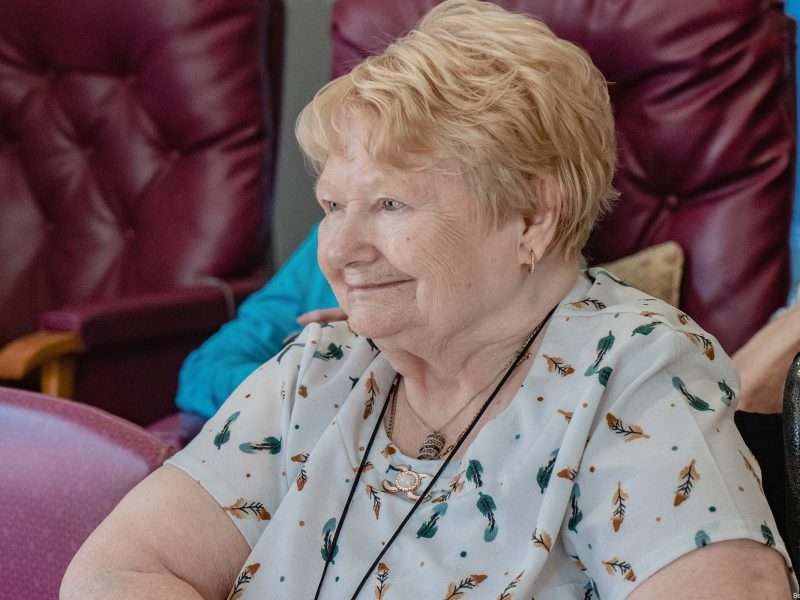 Smiling senior woman in common area seating.