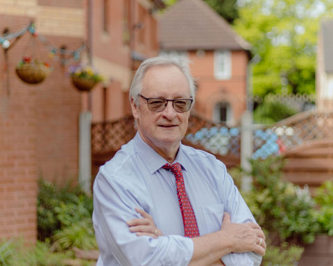 Senior man smiling in garden area of care home.