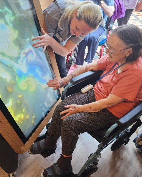 Staff assists a resident with a digital touchscreen.
