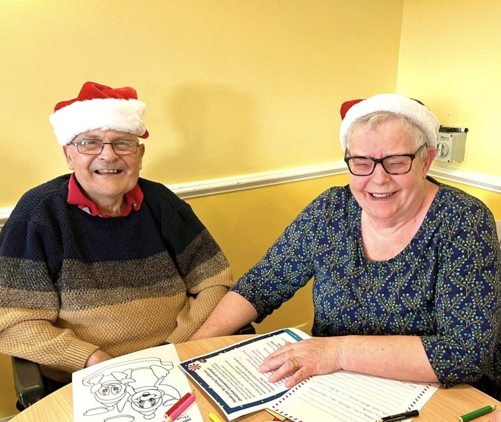Two residents celebrating with Santa hats.