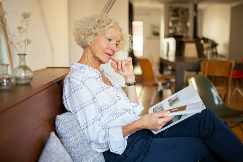 Senior woman enjoying a magazine in a cozy interior.
