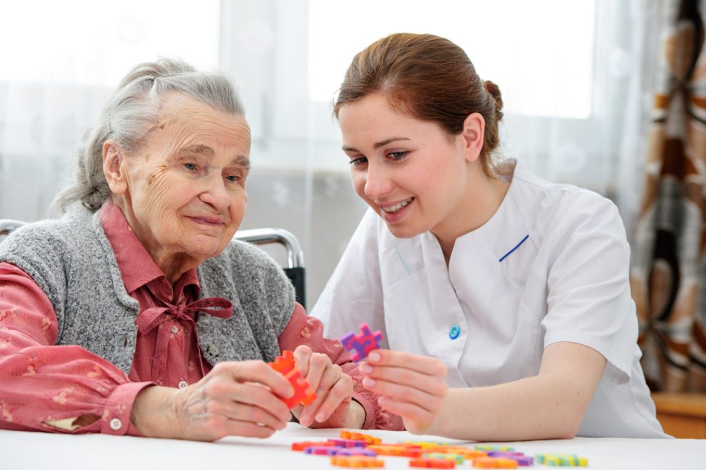 Senior resident and caregiver enjoying a puzzle activity.