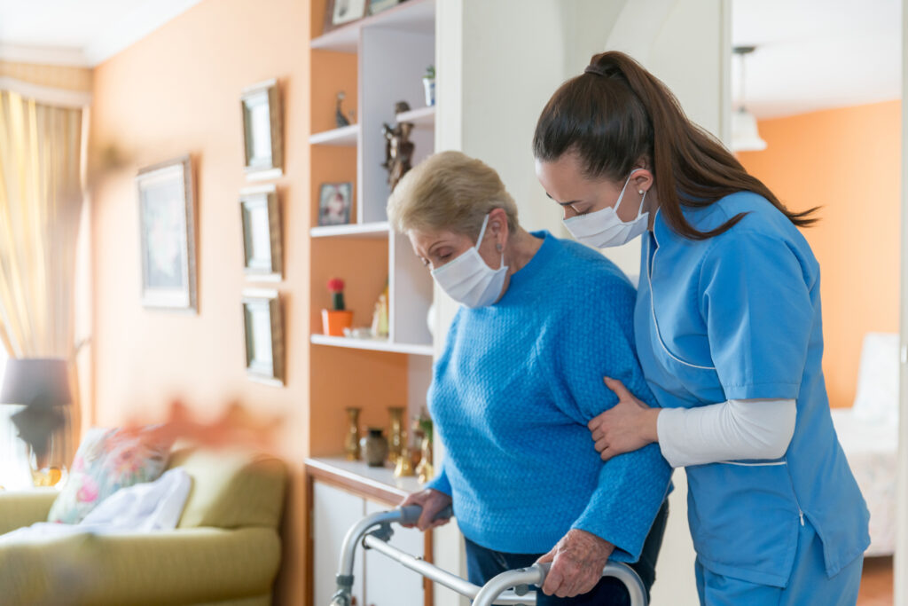Caregiver assisting senior with a walker indoors.