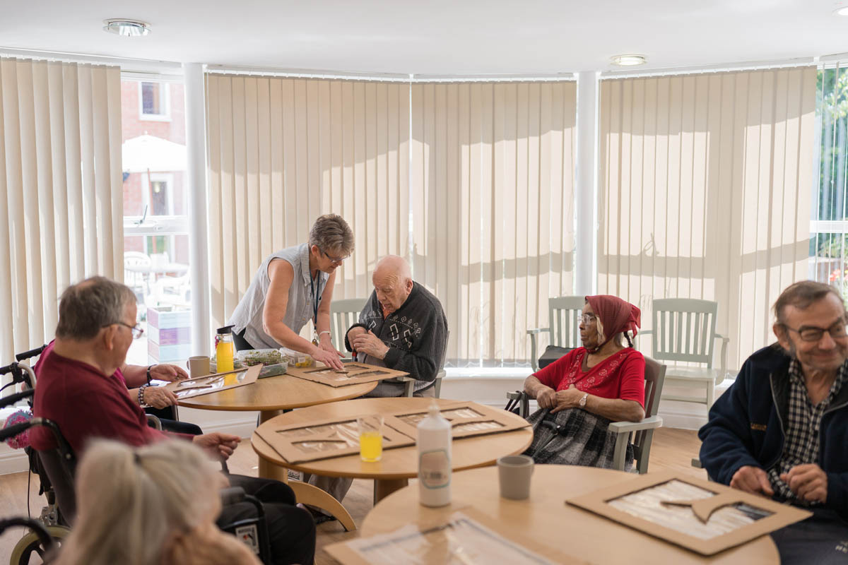 Residents engaged in an activity with staff assistance.