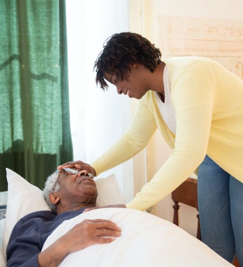 Caregiver assisting an elderly man in bed