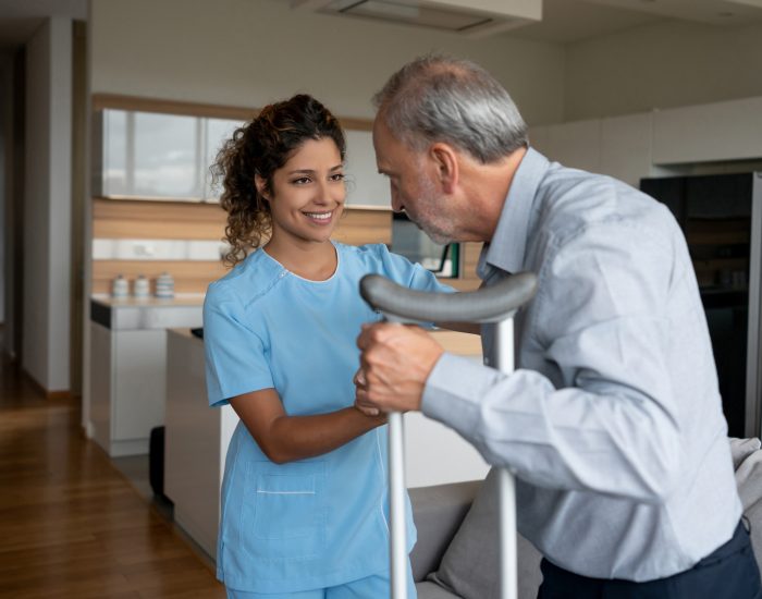 Staff assisting resident with crutches