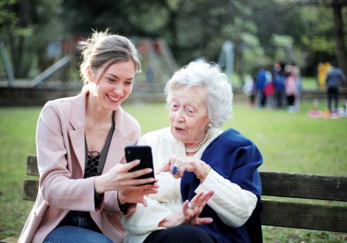 Elderly woman and caregiver sharing a moment outdoors
