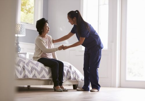 Healthcare staff assisting a resident in a room
