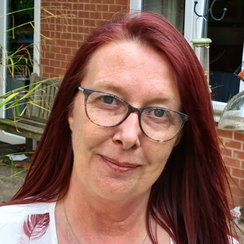 A smiling woman with red hair, outdoors.