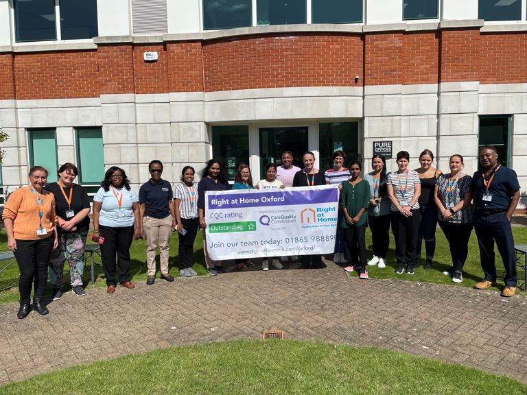 Group of staff members holding a banner outside the facility.