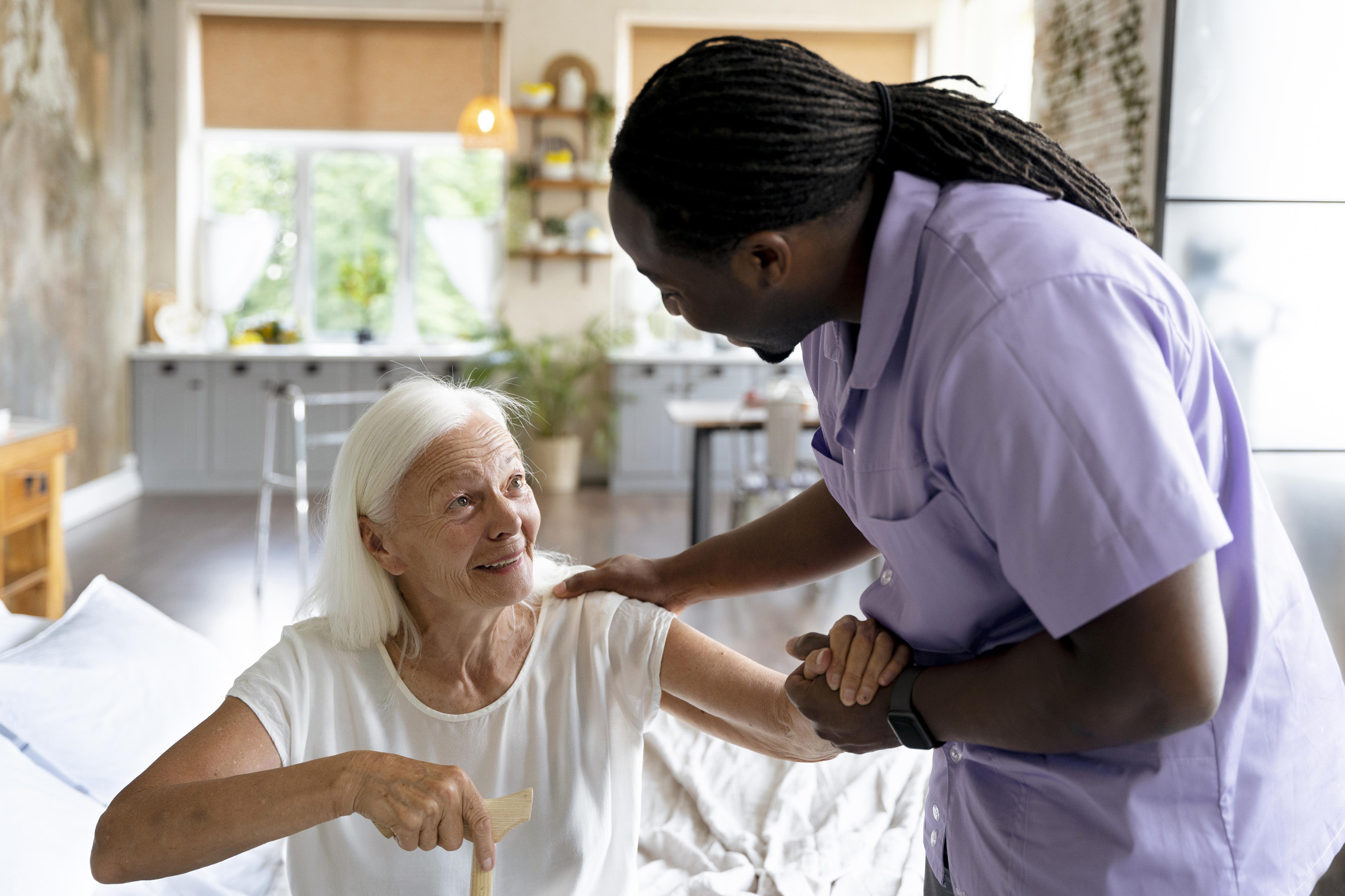 A caregiver interacting with a senior woman in a cozy room.
