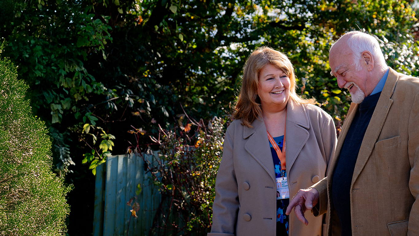 Caregiver and resident walking in the garden.