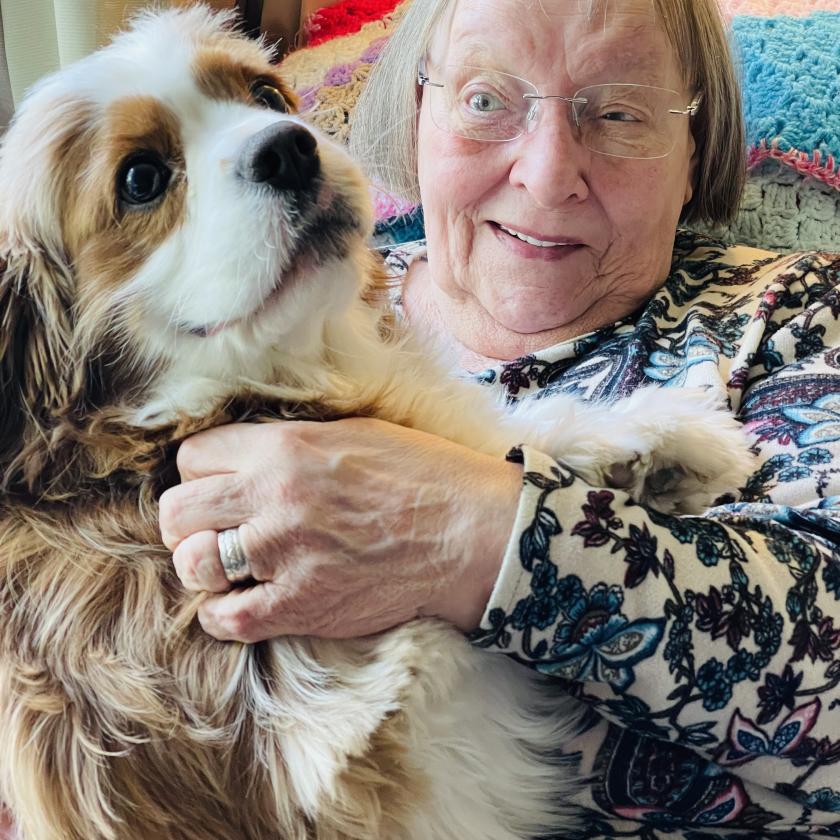 Senior woman holding a dog, smiling warmly.