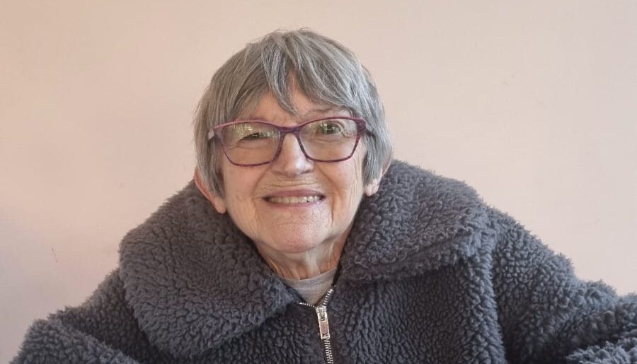Elderly woman smiling warmly at the camera.