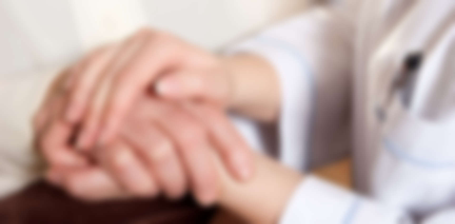 A caregiver gently holding a resident's hands.
