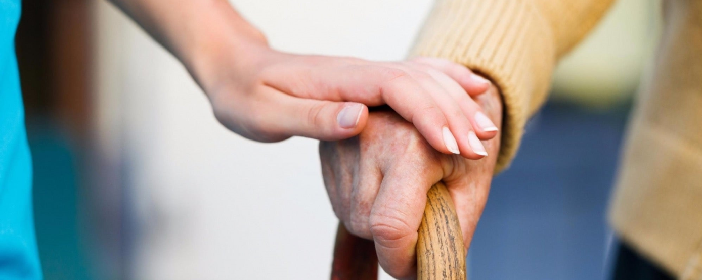 A caregiver holding an elderly person's hand