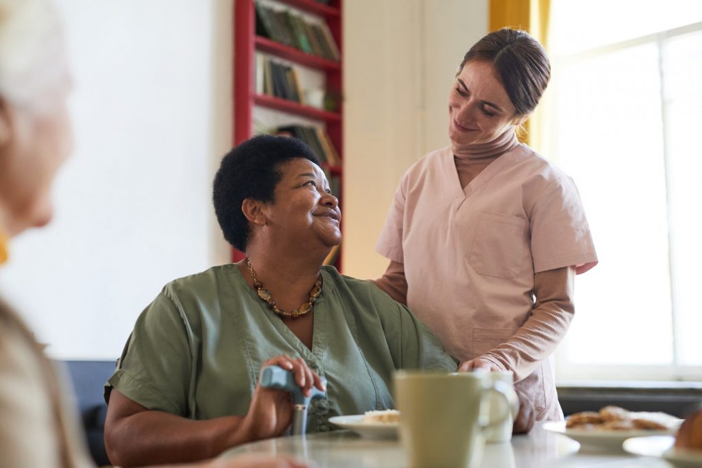 Caregiver and resident interacting warmly indoors.
