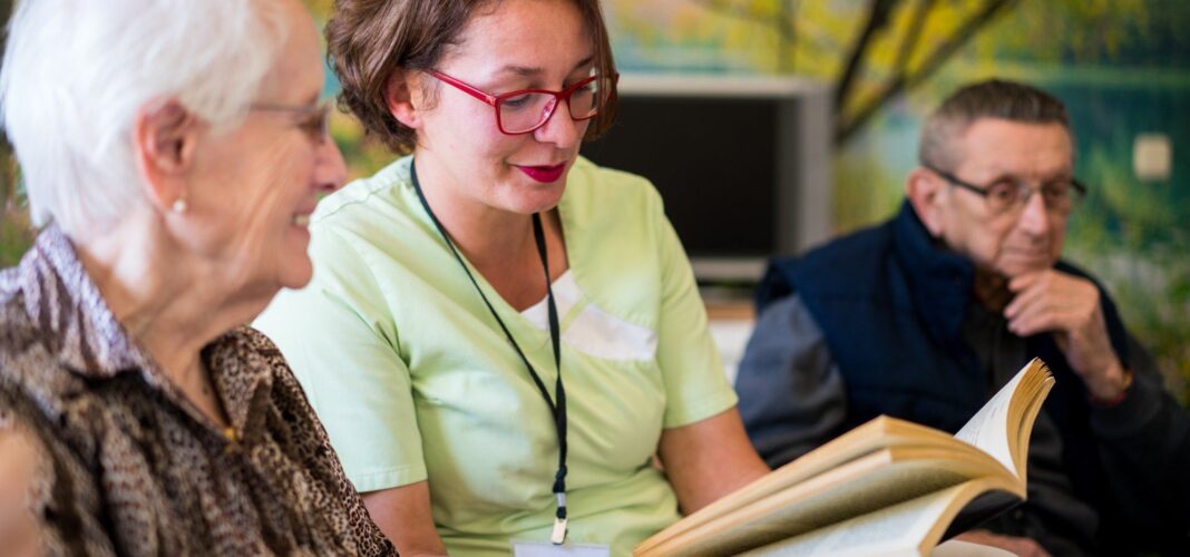 Staff reading with residents in a common area.
