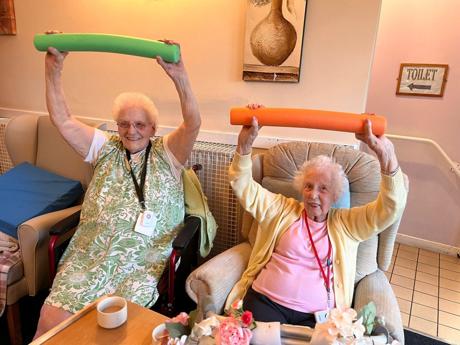 Two elderly women engaging in a fun exercise activity