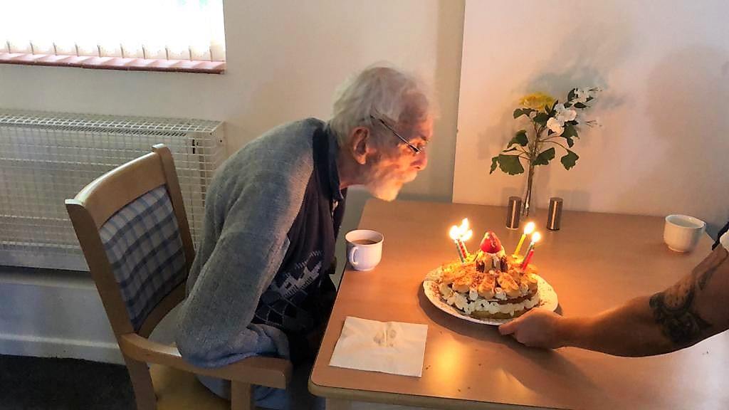 Elderly man celebrating a birthday with cake.