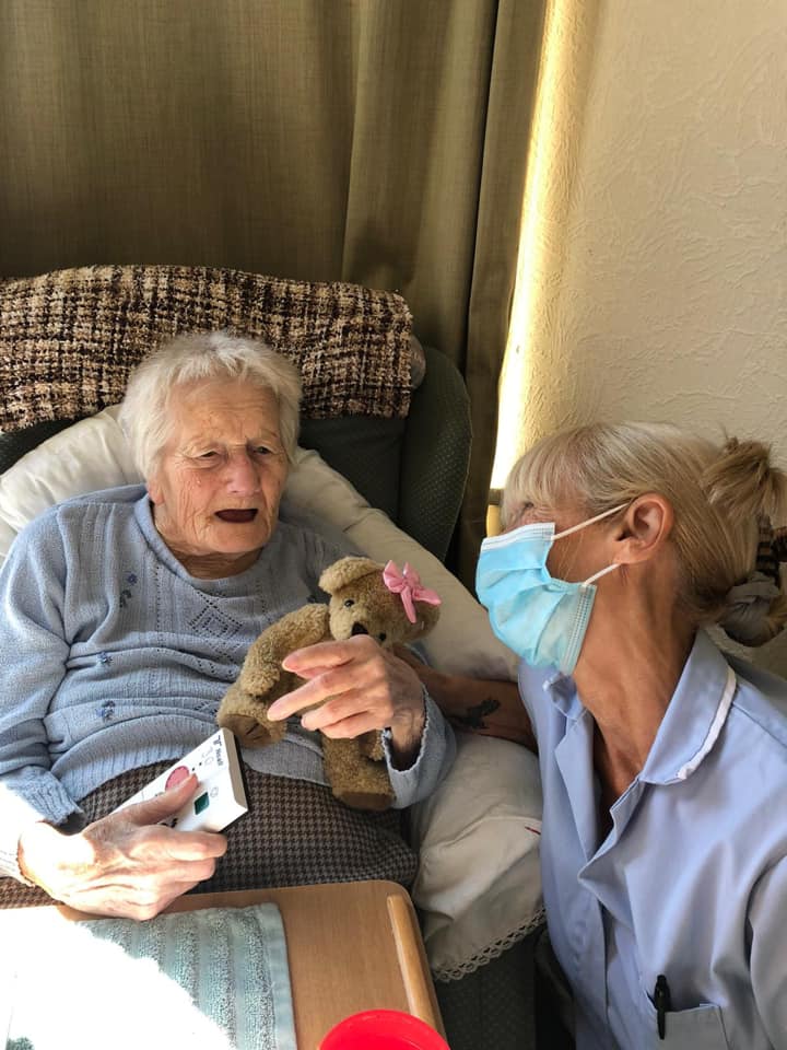 Resident enjoying time with staff and a teddy bear.