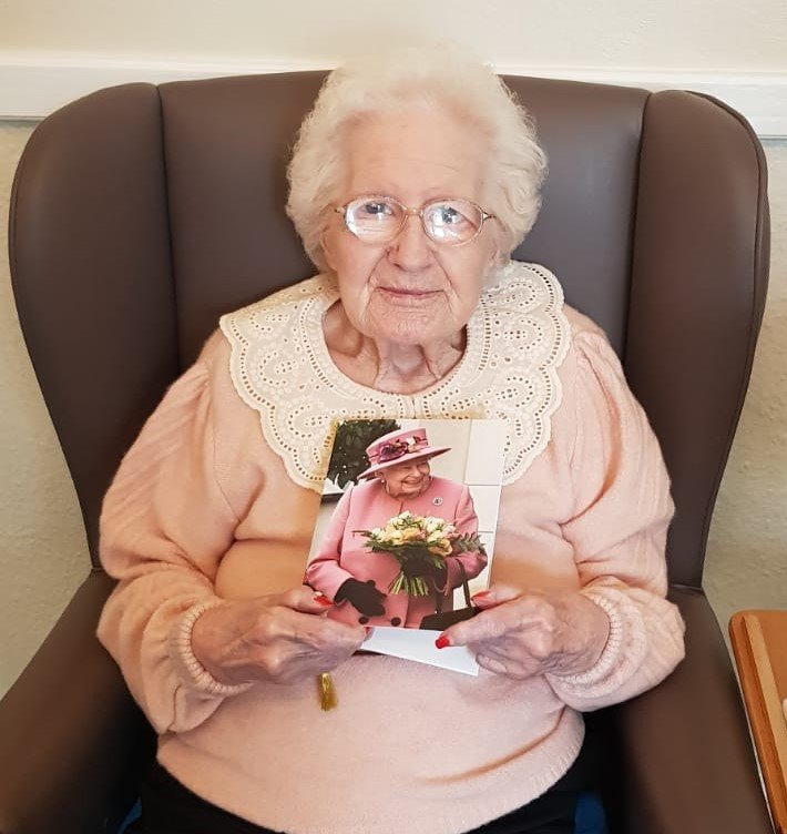 Elderly woman holding a greeting card in a cozy chair