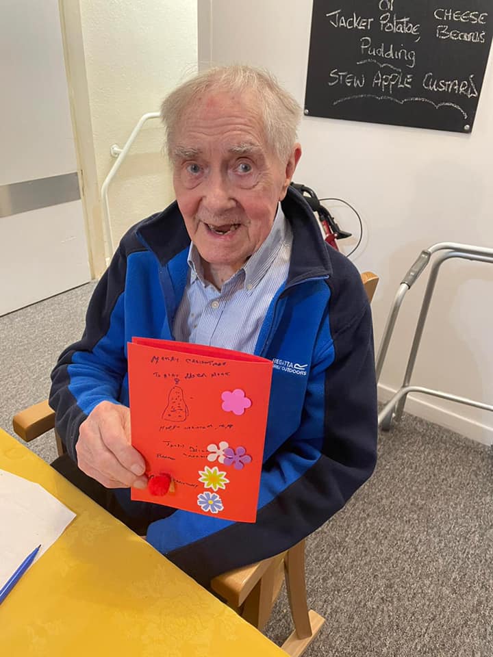 Resident holding a decorated card at a table.