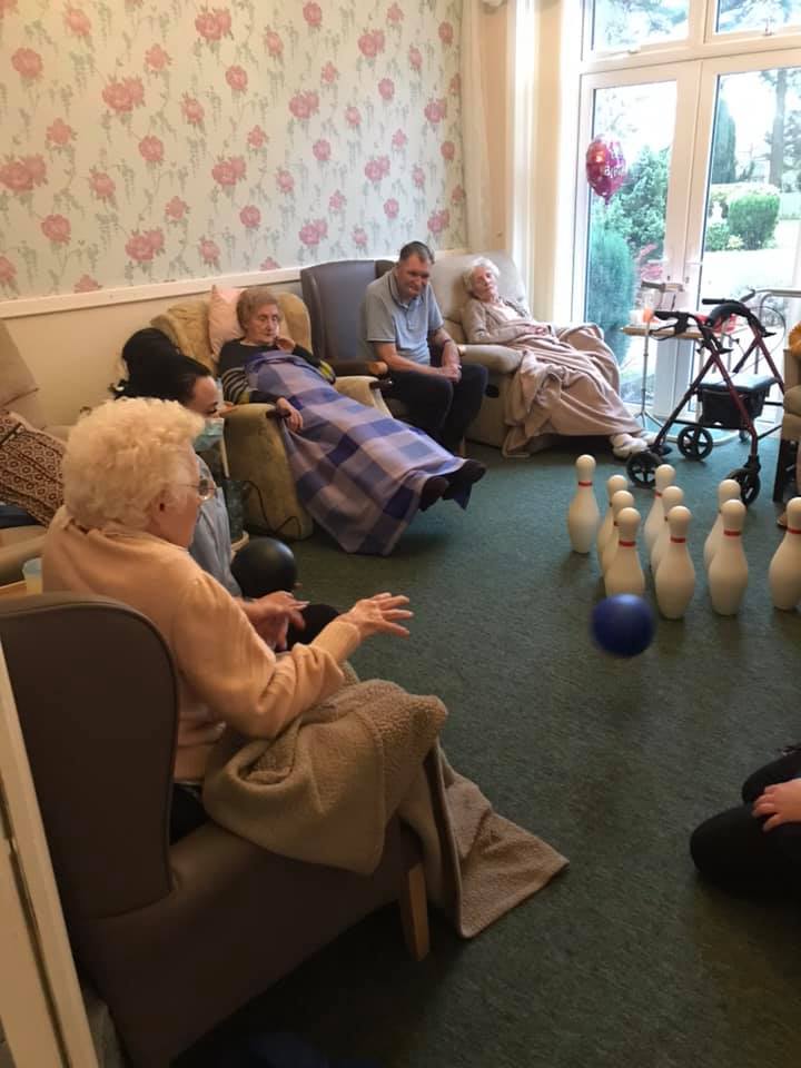 Residents participating in a bowling activity indoors.