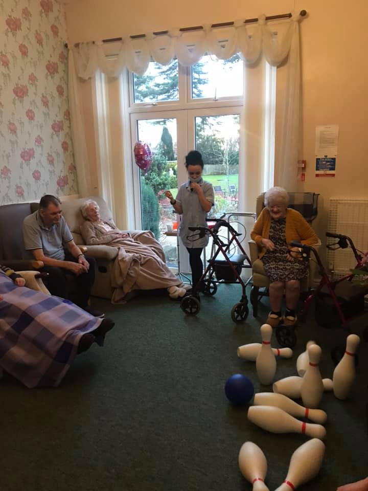 Residents participating in a bowling activity indoors.