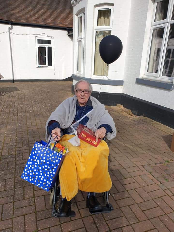 Resident celebrating outdoors with gifts and a balloon.