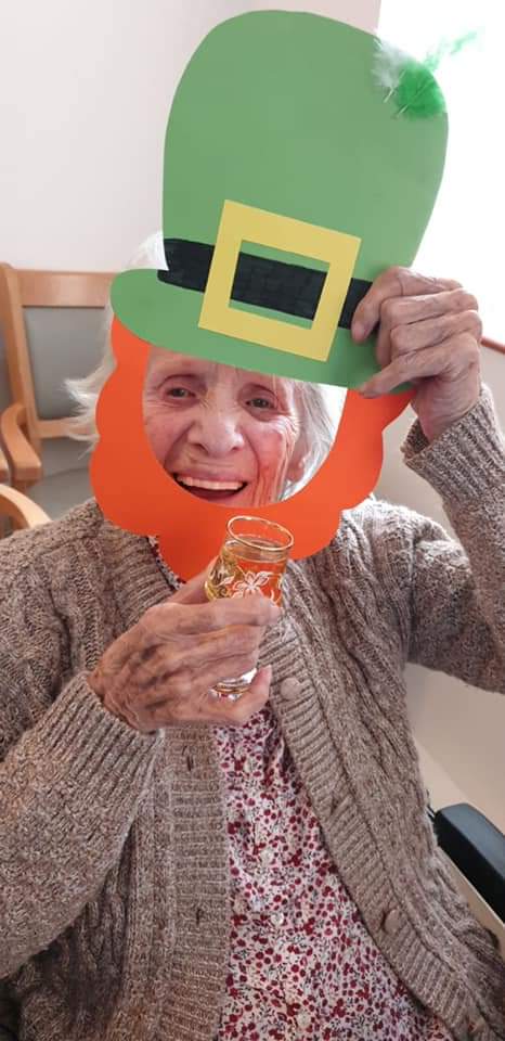Senior resident celebrating with festive hat and drink.