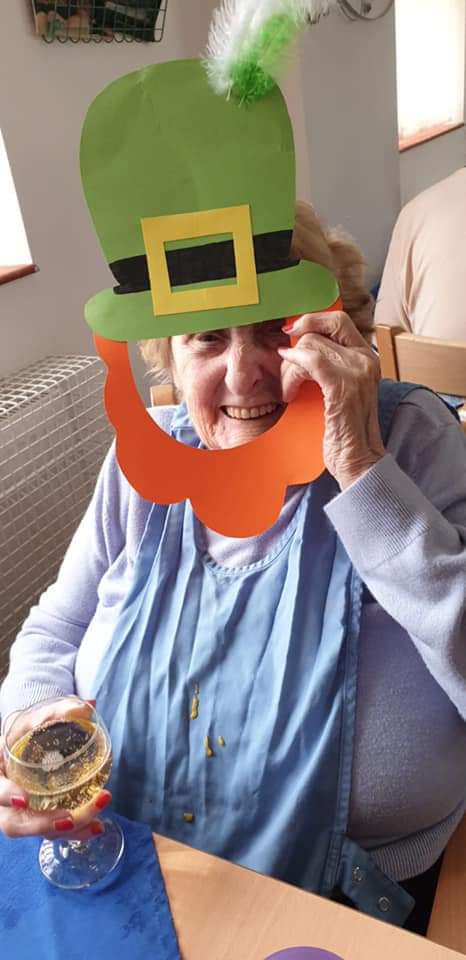 Elderly woman smiling with festive accessories.