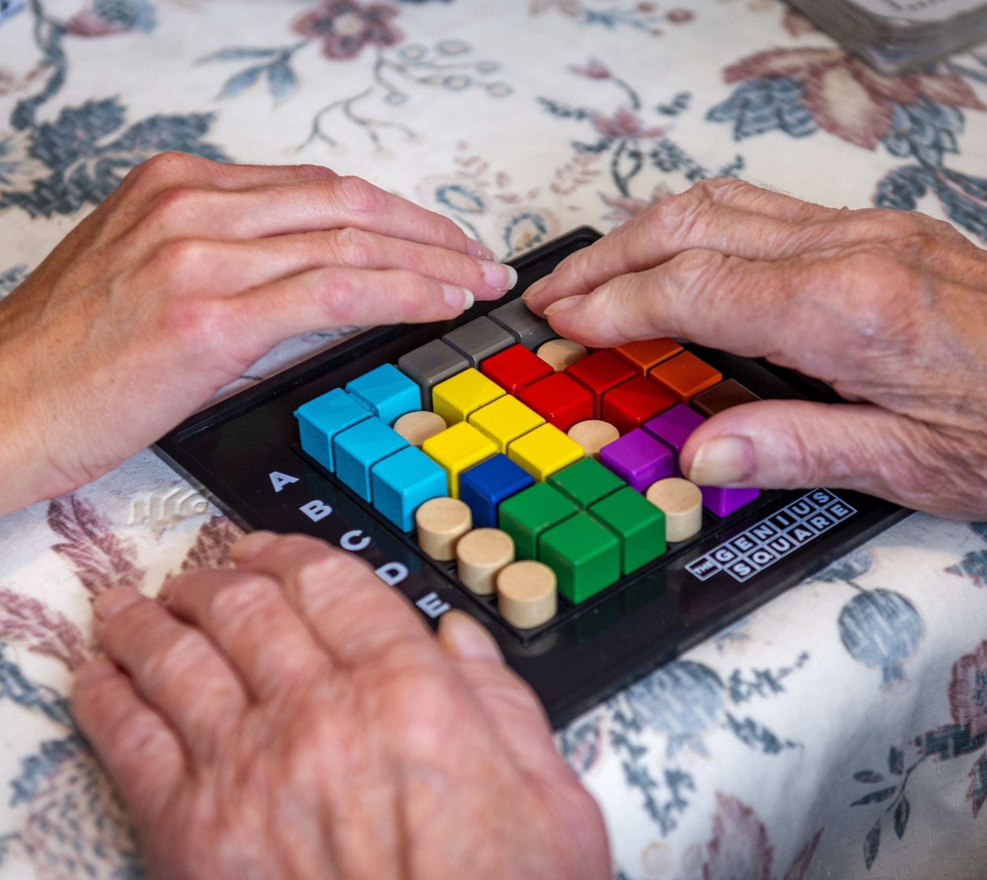 Two hands playing a colorful tabletop game.