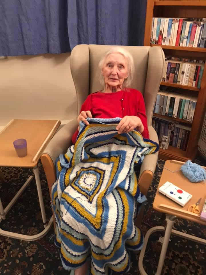 Senior resident knitting in a cozy common area.