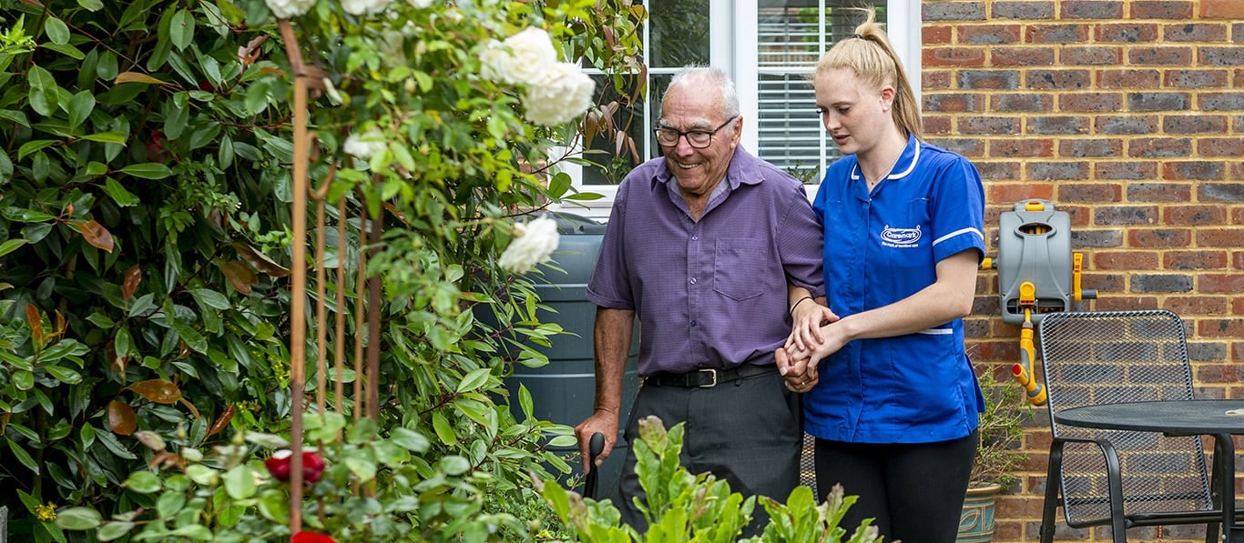 Staff assisting a resident in a garden