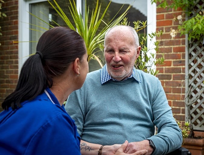 Caregiver and resident engaged in conversation outdoors.