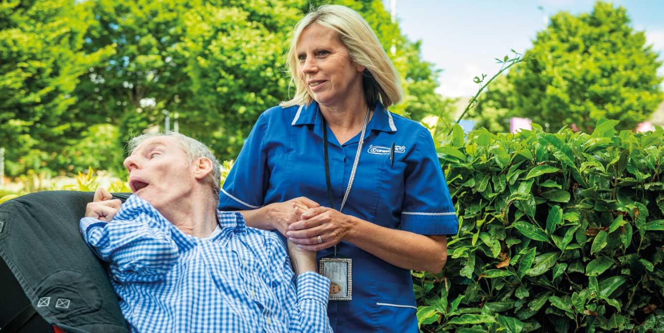 Care staff assisting a resident outdoors.