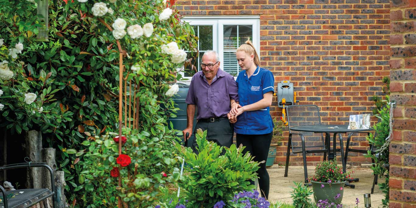 Staff assisting a resident in a garden
