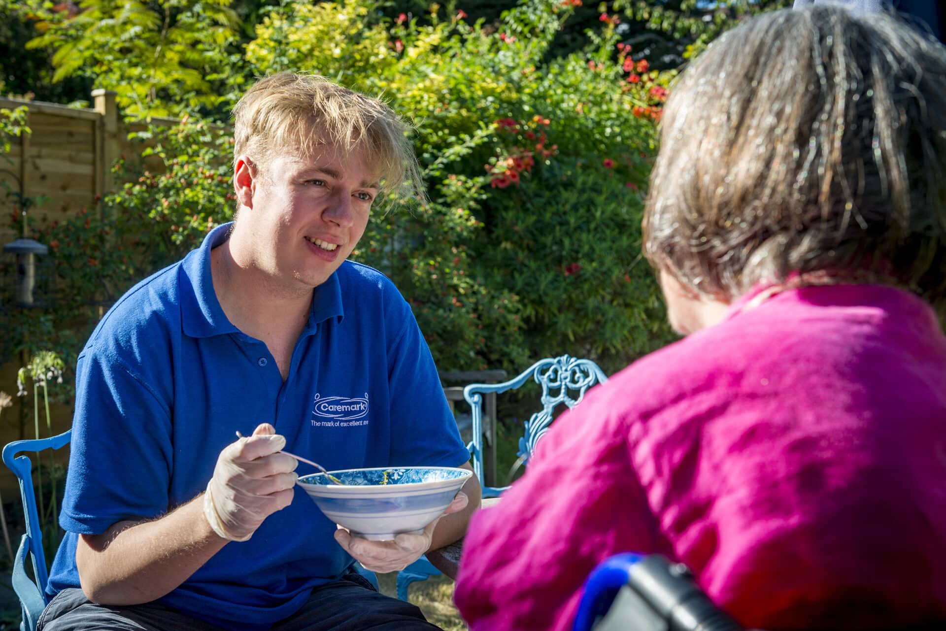 Staff member feeding a resident outdoors.