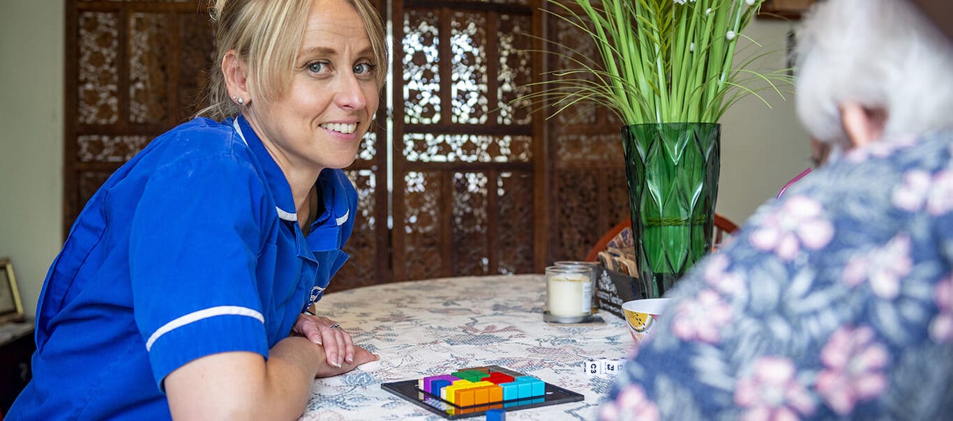 Staff member interacting with a resident at a table.