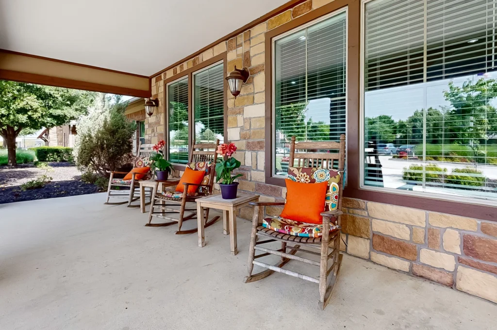Outdoor seating area with rocking chairs and plants.