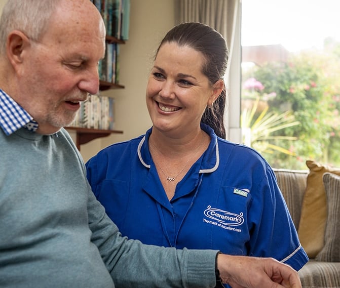 Staff member interacting with resident in a cozy interior.