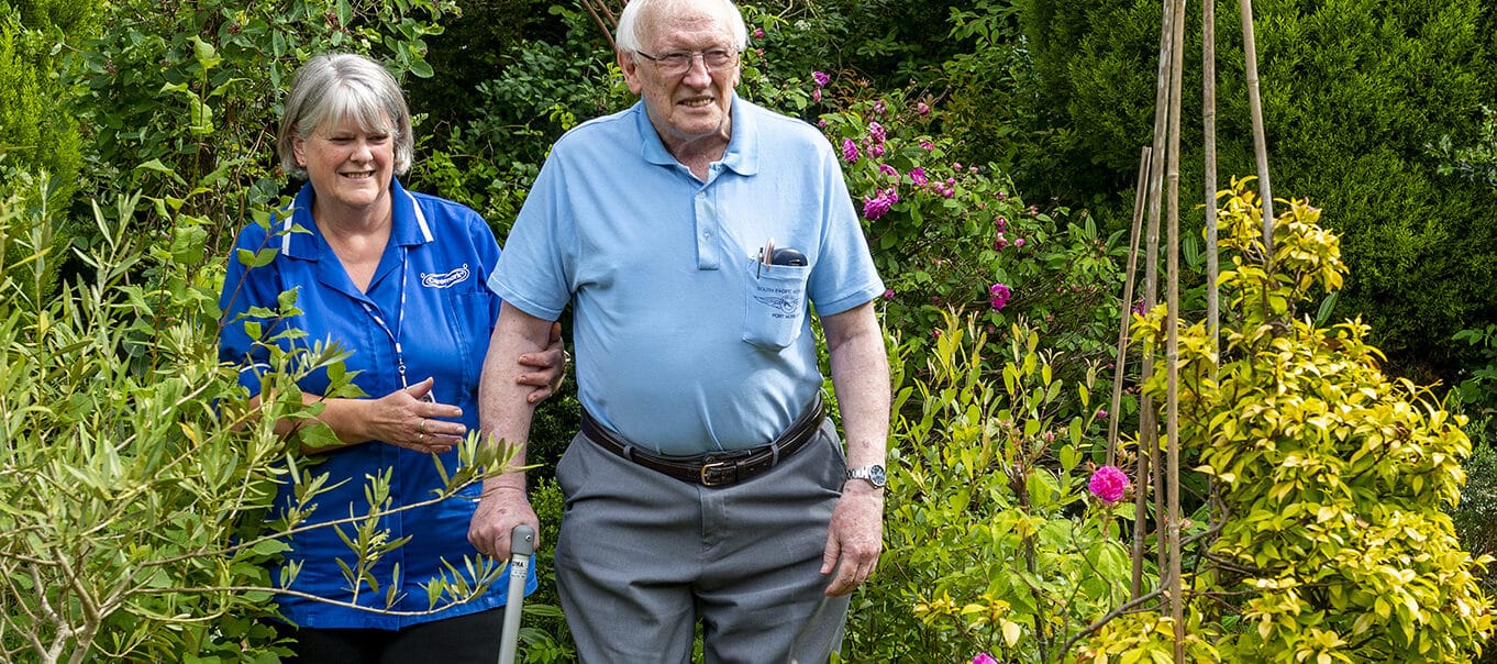 Staff assisting a resident in a garden.