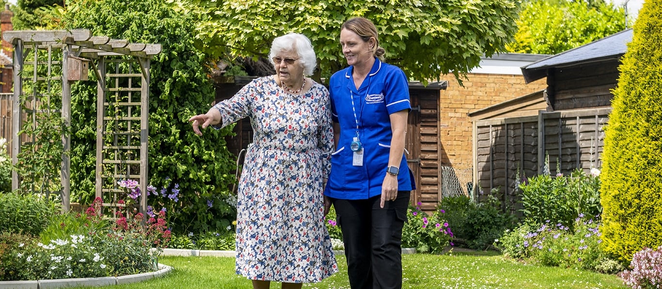 Resident and staff walking in a garden