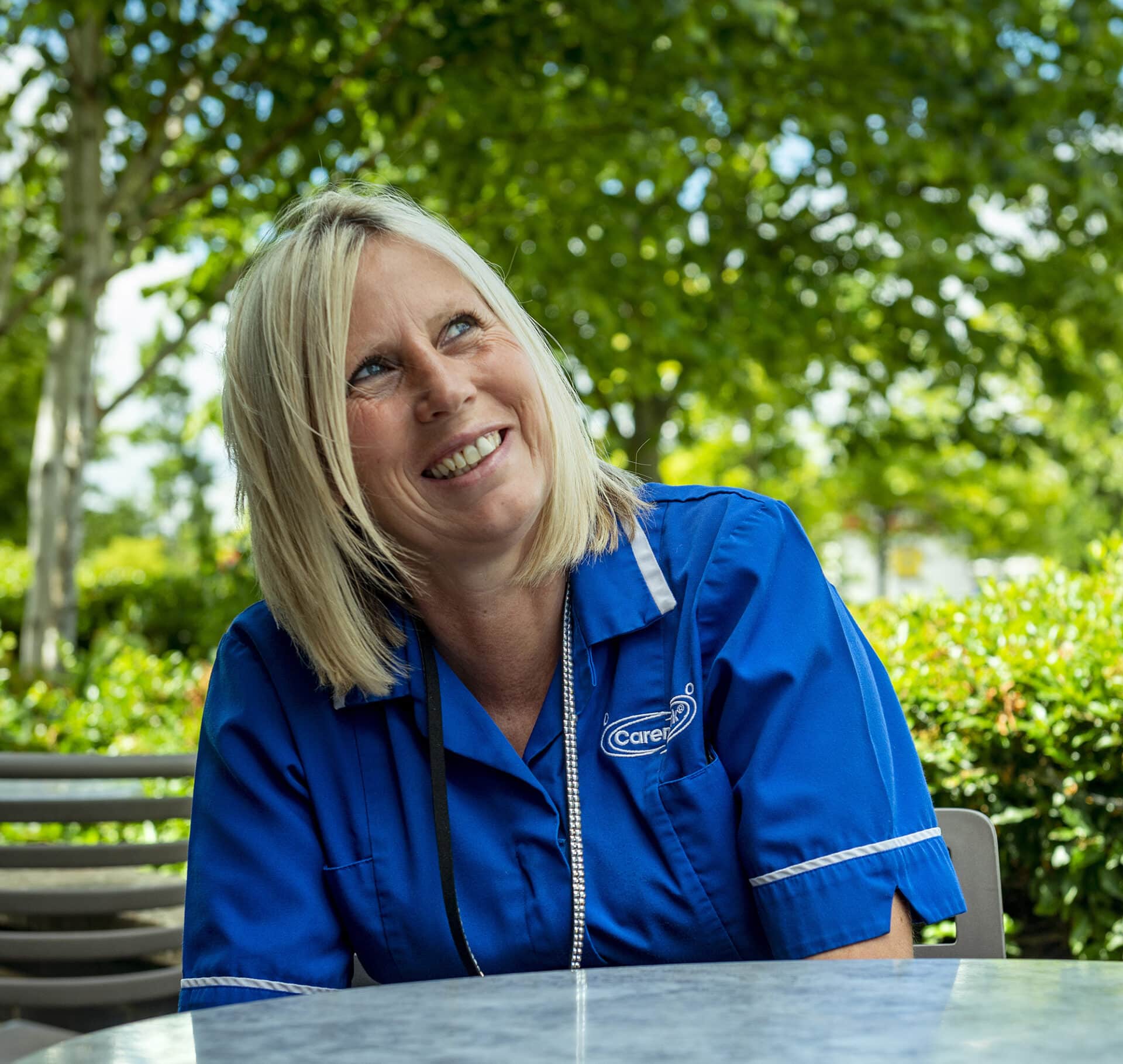 Staff member smiling outdoors in a garden area.