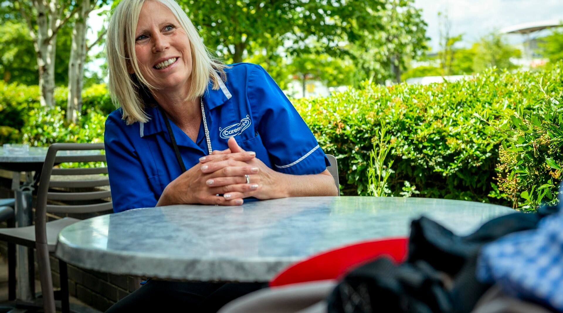 Staff member smiling outdoors at a table.