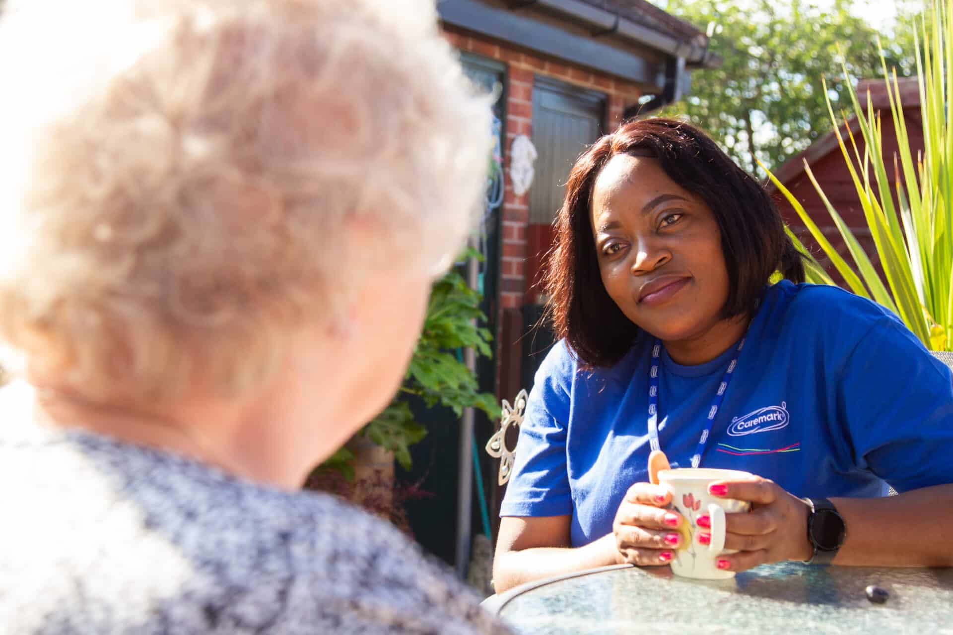 A caregiver talk with a resident outdoors.